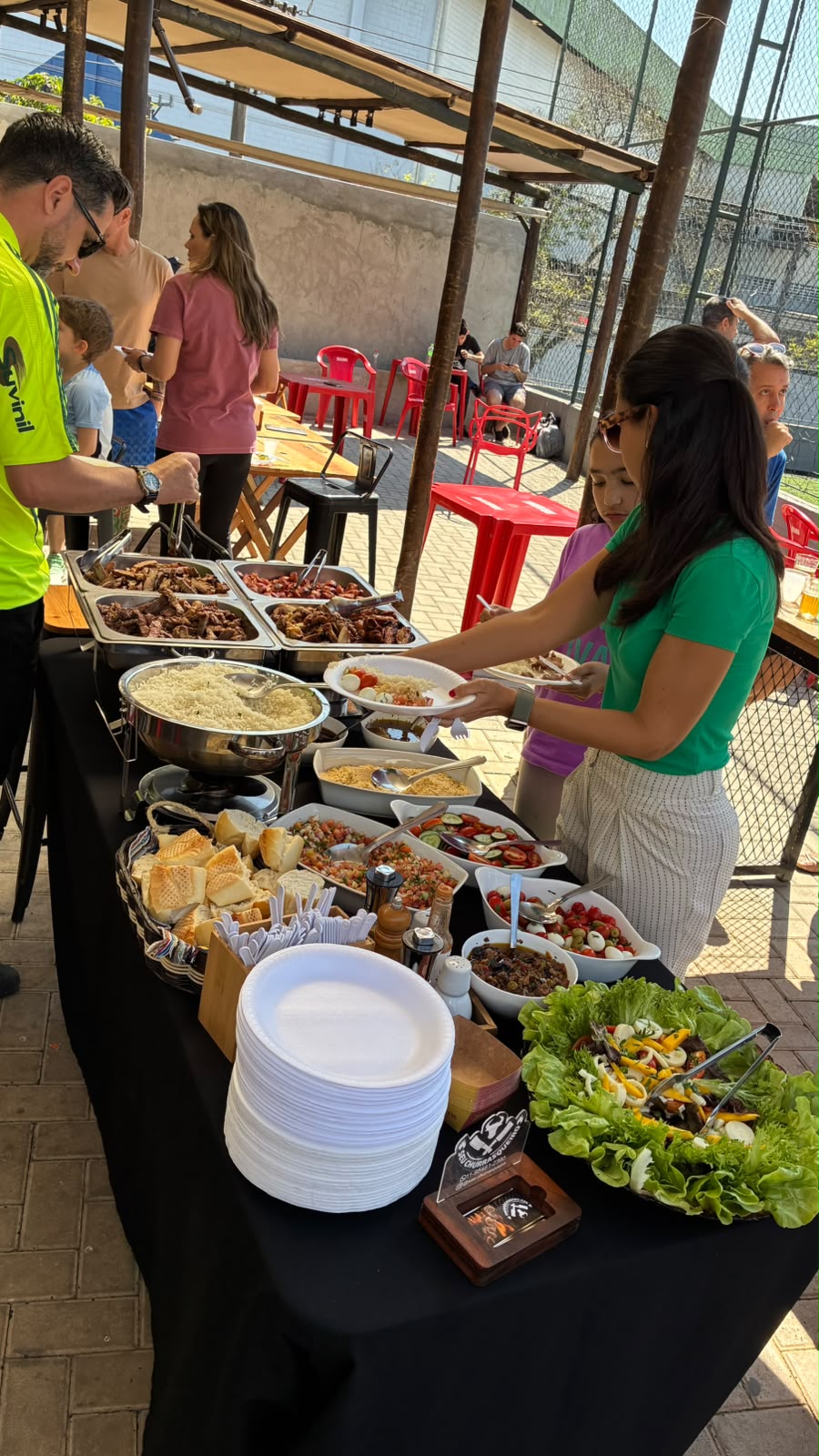 Convidados se servindo de carnes, saladas e acompanhamentos no buffet de churrasco