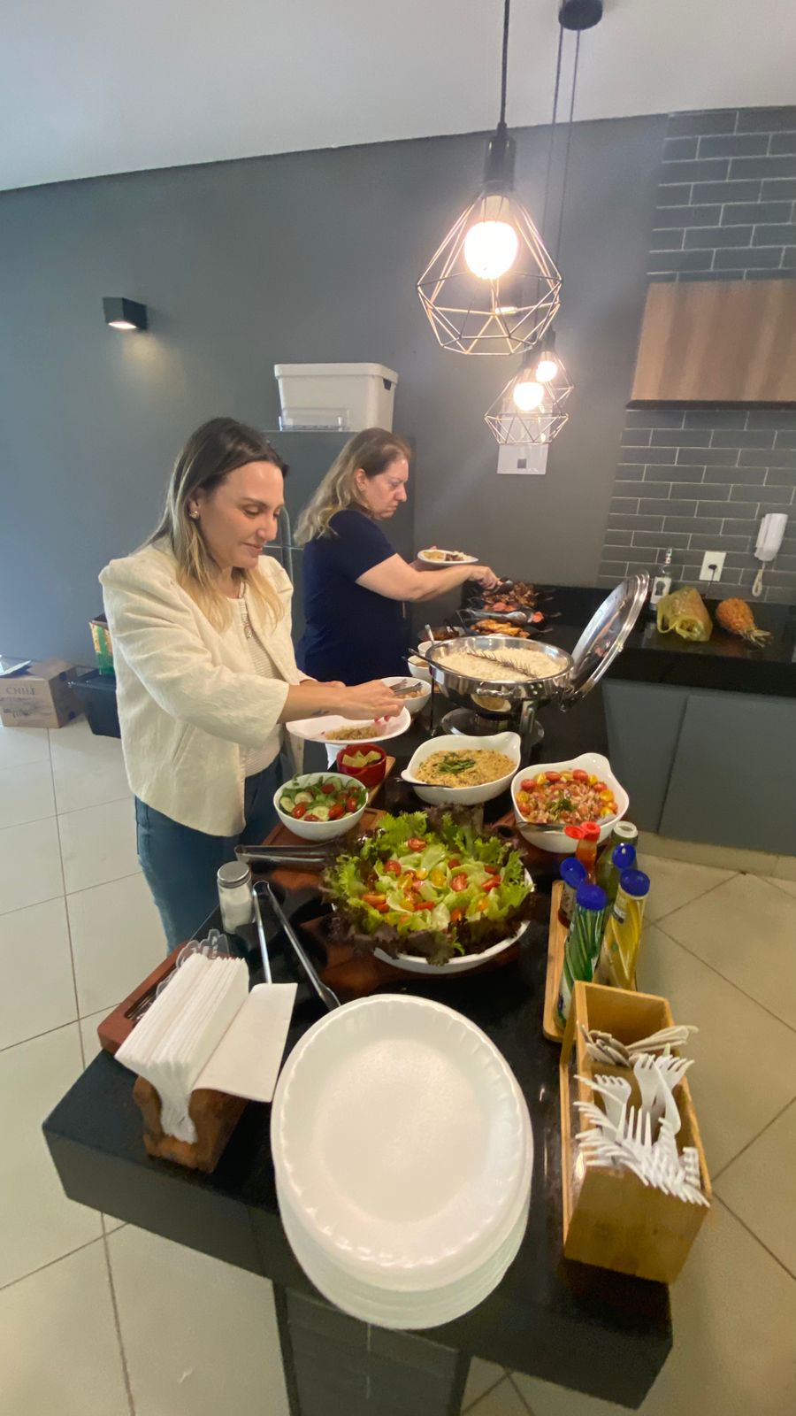 Convidadas se servindo de saladas e churrasco em um evento