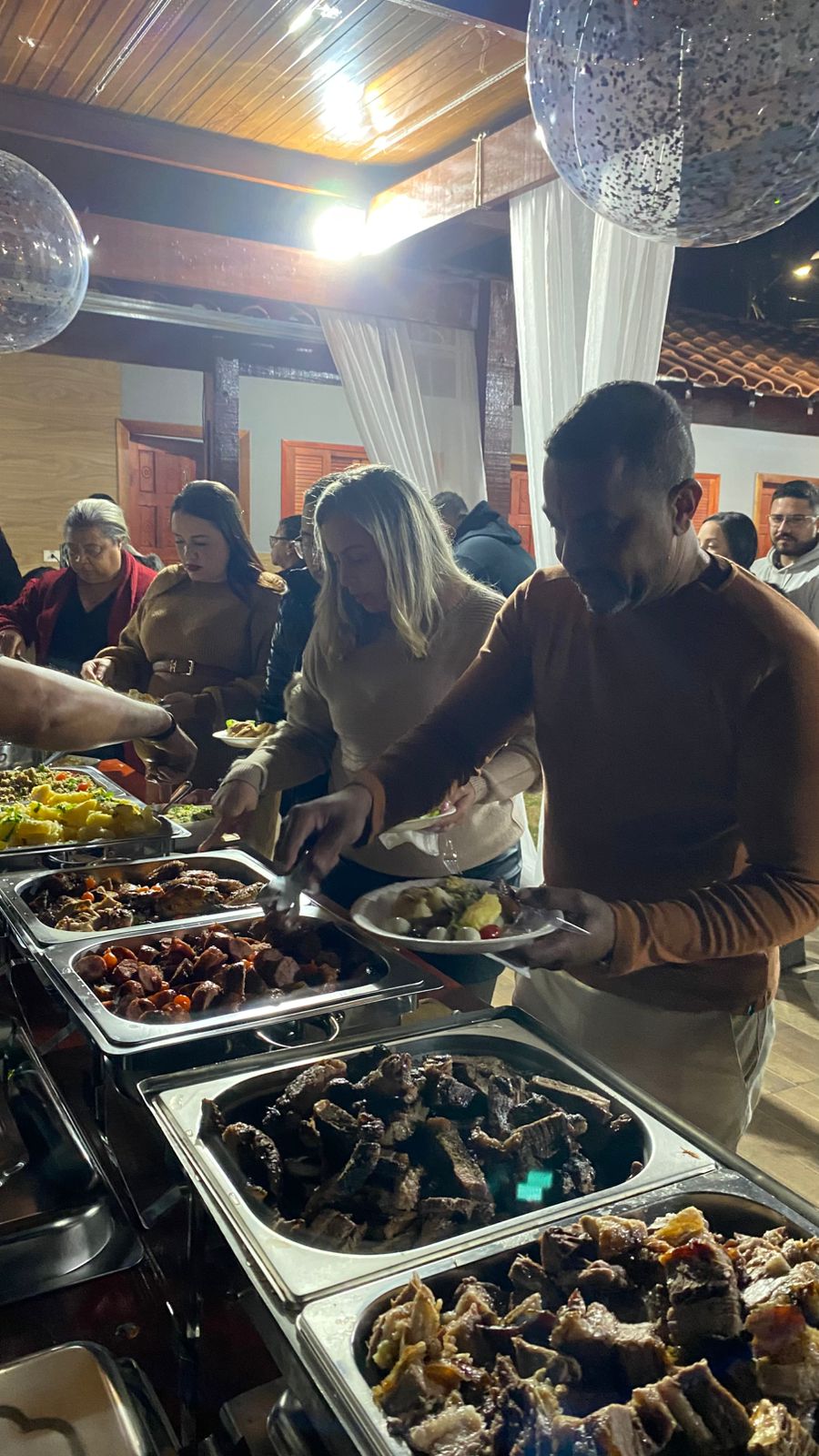 Convidados reunidos junto ao buffet durante uma celebração à noite