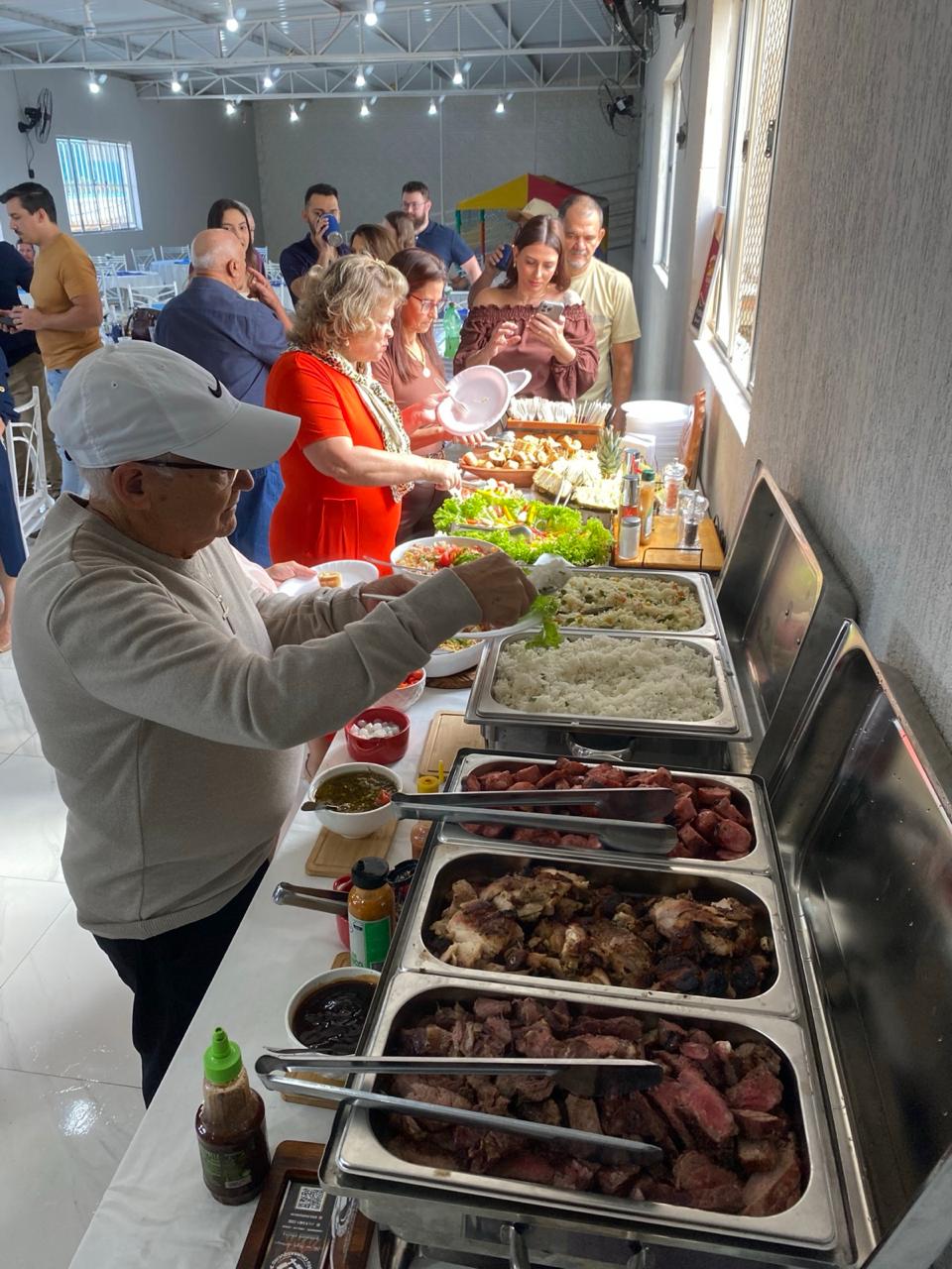 Convidados compartilhando a mesa de buffet em uma celebração no salão